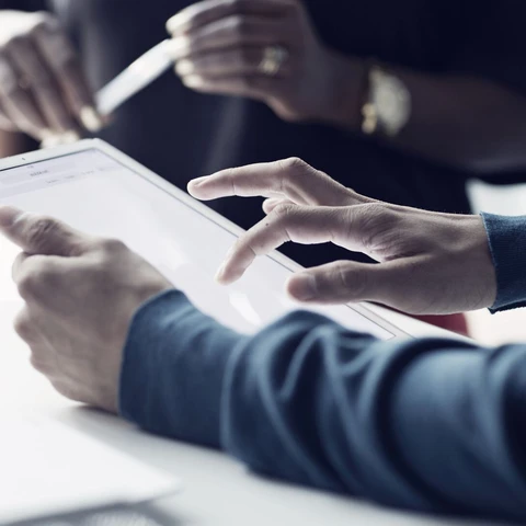 Close-up of co-workers standing at desk with laptop
