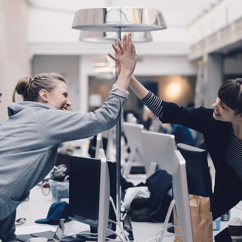 Group of happy people giving each other high five in office space
