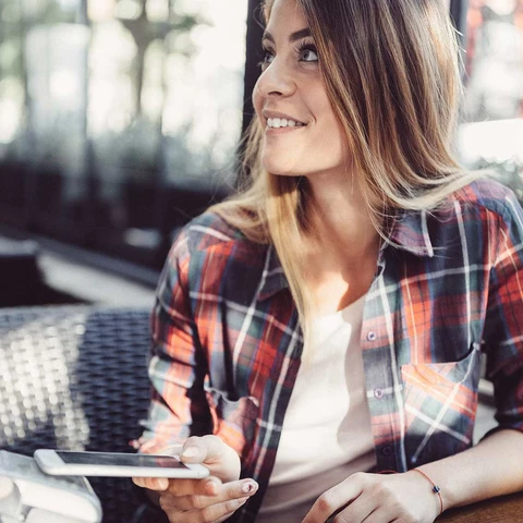 Young woman performing a payment with her mobile phone in an outside restaurant