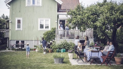 mature-friends-having-garden-party-while-children-are-playing-in-backyard