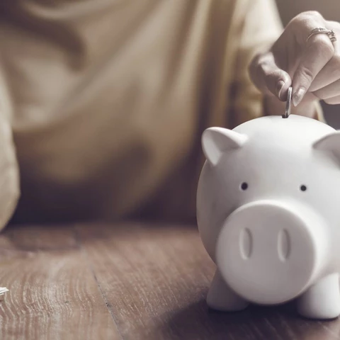 woman-putting-coin-in-piggy-bank