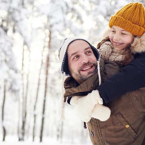 man carrying kid in snow