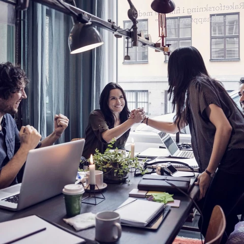 Happy businesswomen holding hands in meeting at creative office