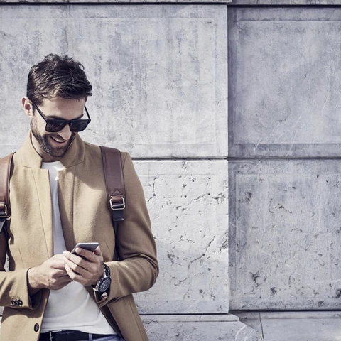 smiling businessman using phone against building