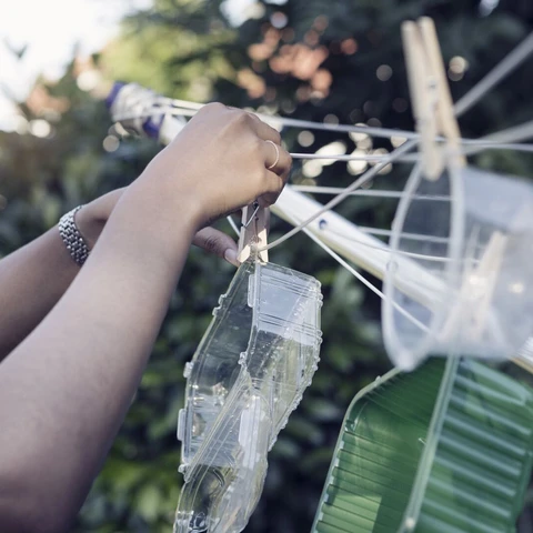 woman-hanging-washed-plastic-containers-onto-a-clothesline