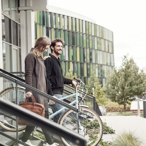 Smiling couple leaving building with bicycles