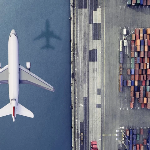 Airplane flying over cargo at a port