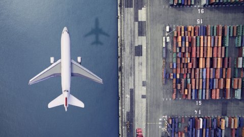Airplane flying over cargo at a port