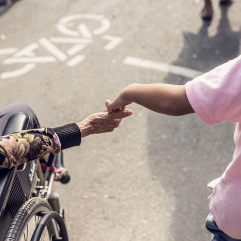 Person in wheel chair and child holding hands