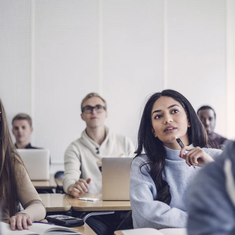 Male and female students sitting at desk in classroom