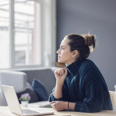 Profile of woman with laptop and credit card looking out the window