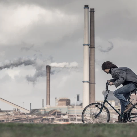 Person-riding-bike-in-front-of-factor