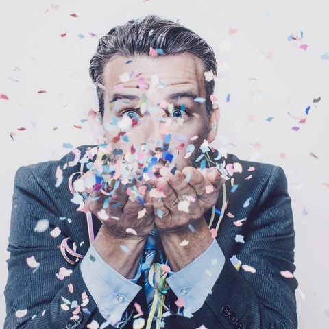 Man in suit blowing confetti