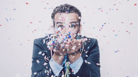 Man in suit blowing confetti