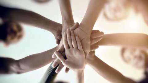 People in a circle with hands in the center