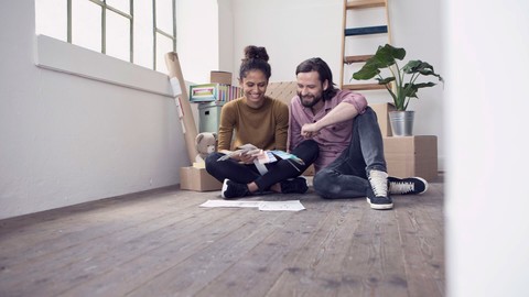 Couple sitting on floor of new flat choosing from color samples