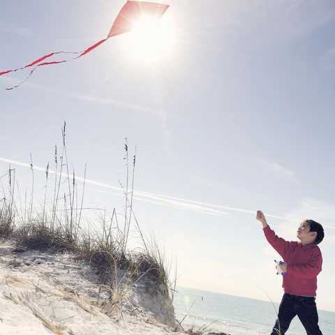 young-boy-flying-a-red-kite-on-beach