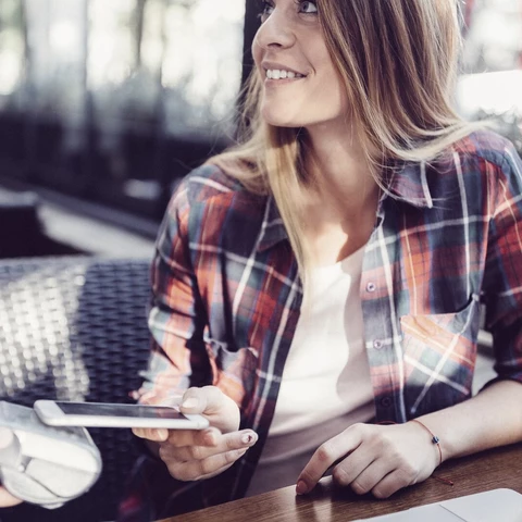 Customer in cafe paying contactless with smartphone