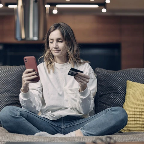 Young woman hold banking credit card, entering payment information in phone