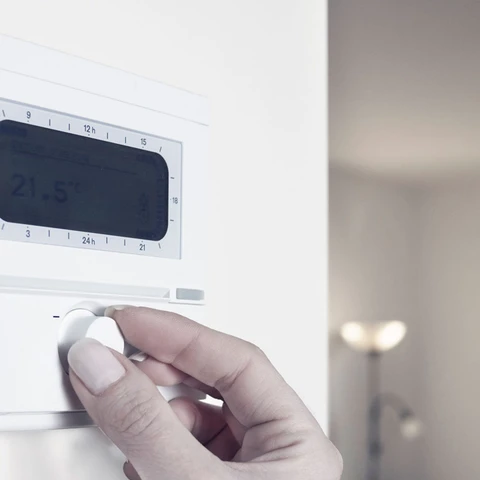 Close up of womans hand adjusting the thermostat