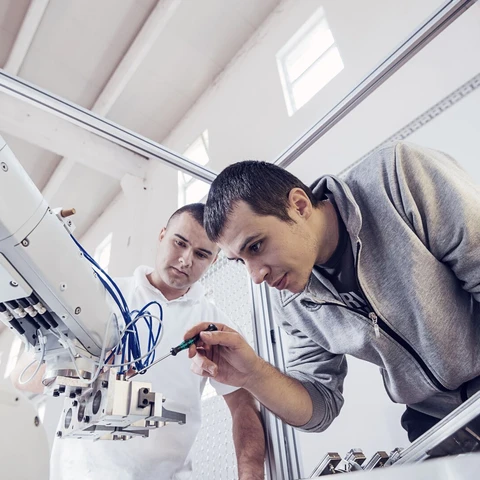 Engineers working on development of automated production line with robotic parts and applied software in order to increase productivity. Precise engineering on electric parts of automated production line.