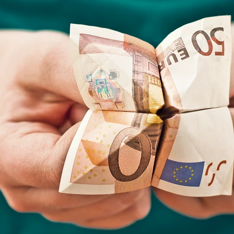 Hands holding a folded euro note