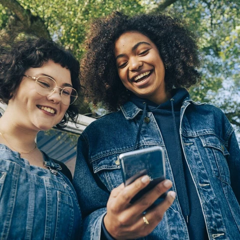 Two young people looking at a mobile phone