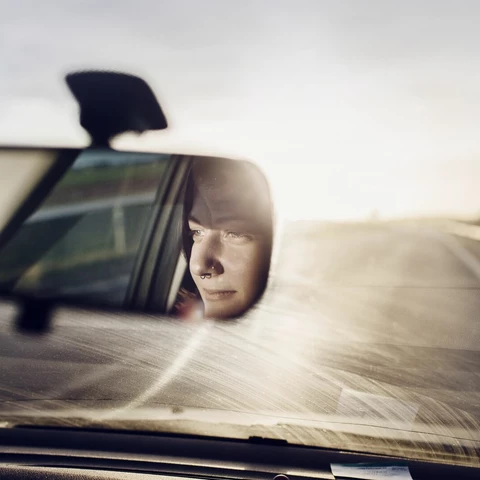 Reflection of a woman in rear view mirror
