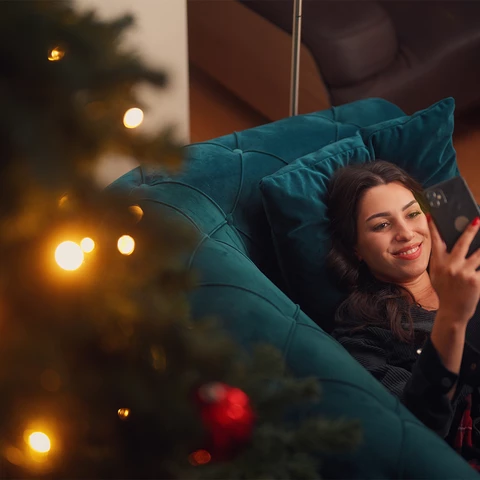 women laying on sofa reading on her phone