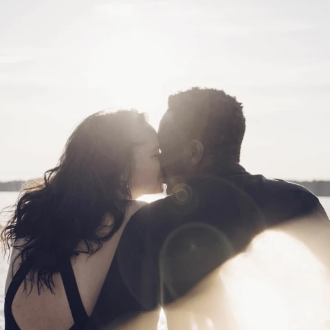 couple-kissing-while-sitting-against-lake