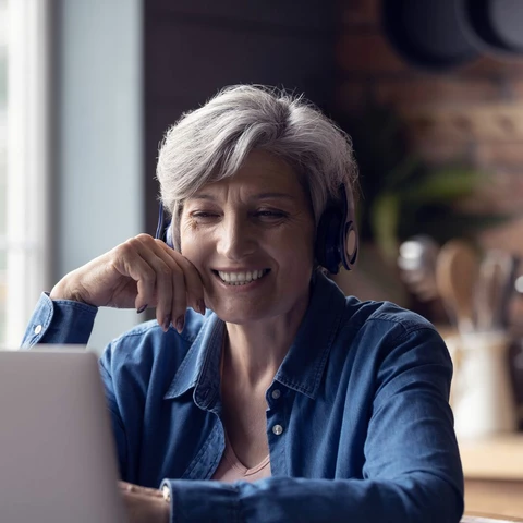 Smart elderly woman watching webinar on laptop