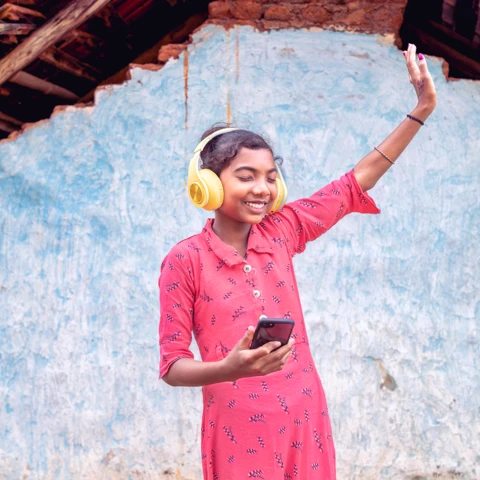 A girl from a tribe in India listening to music with headphones.