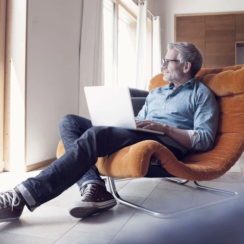 Mature man using laptop in armchair