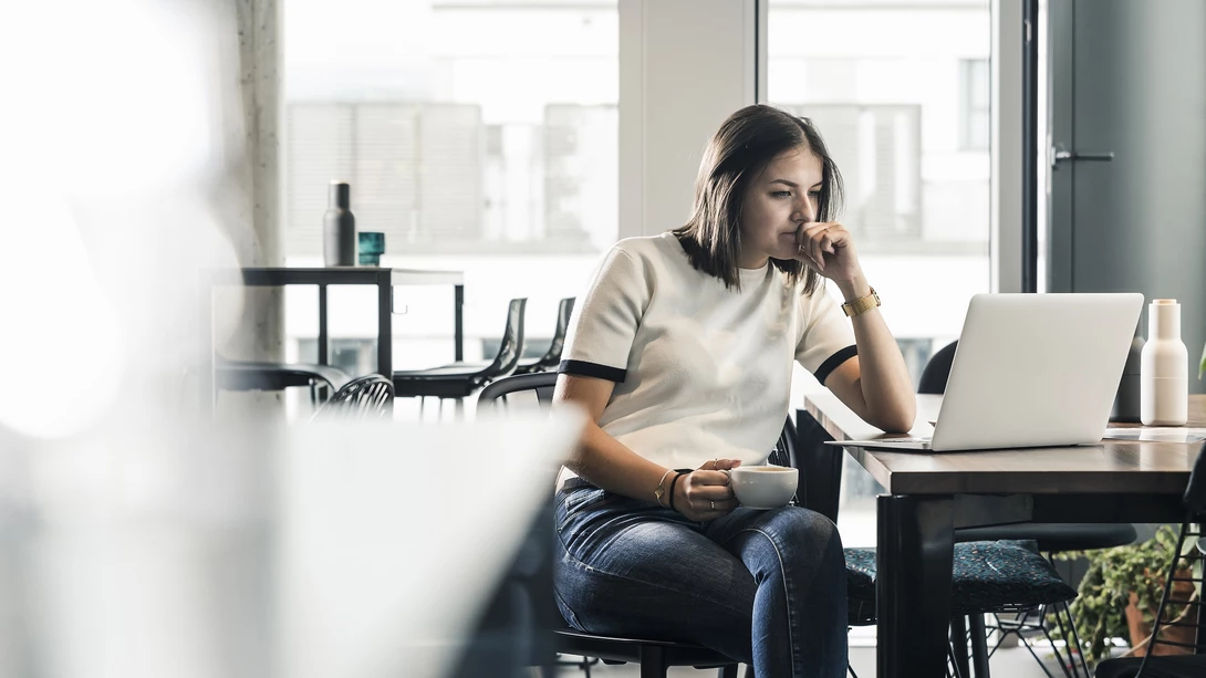 Young woman sitting on a chair and looking at laptop