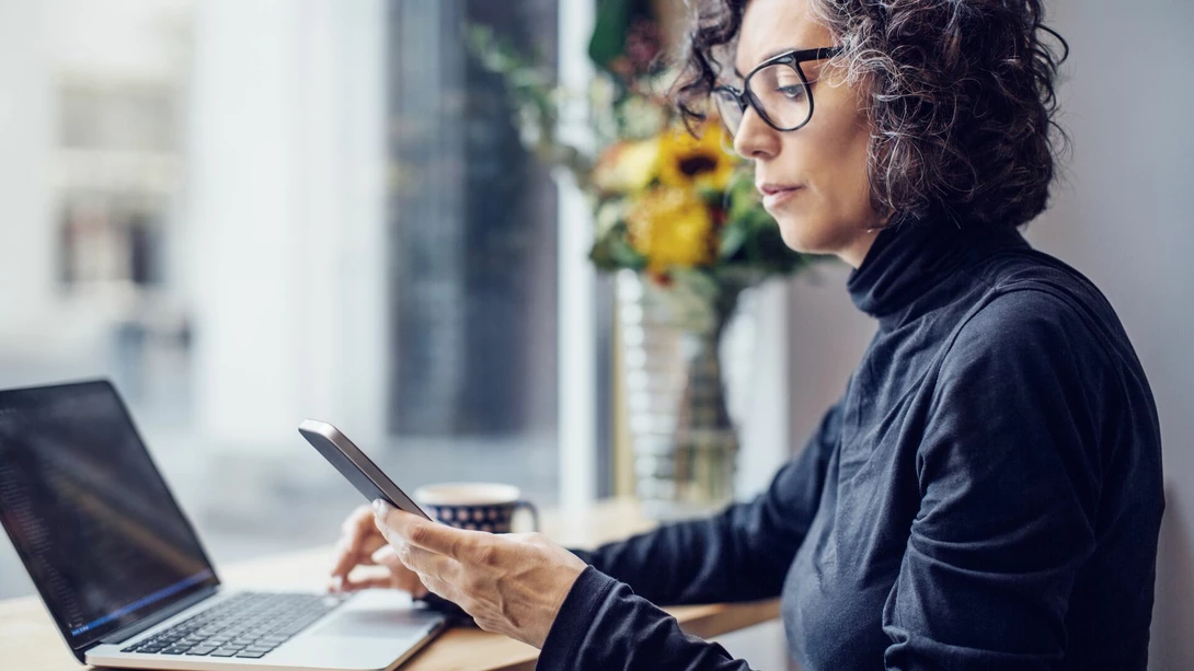 A person at cafe with mobile and laptop at hands