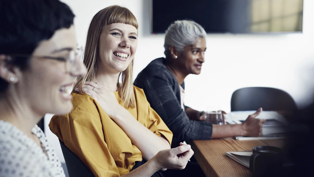 Three persons sitting at an office desk