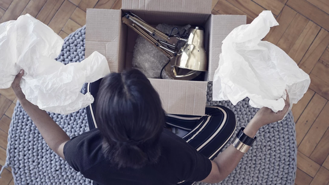 A young woman opening a box with lamp at home