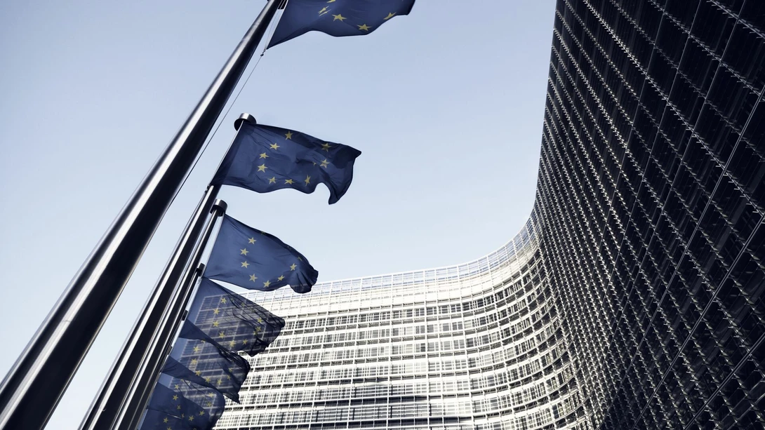 Eurooopan komission rakennus, jonka edessä EU:n liput liehuvat tuulessa