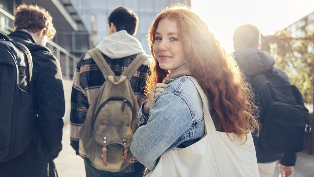 Student walking with friends, looking at camera