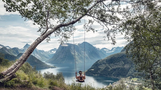 Women on a swing in Norway overlooking water and mountains