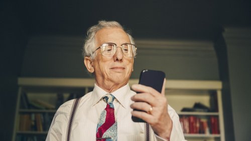 Äldre man tittar på sin mobiltelefon. 